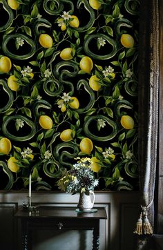 the wallpaper is decorated with lemons and green leaves, while white flowers sit on a table in front of it