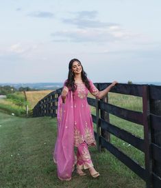 a woman standing next to a wooden fence