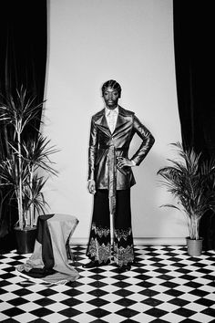 a black and white photo of a man in a suit standing on a checkered floor