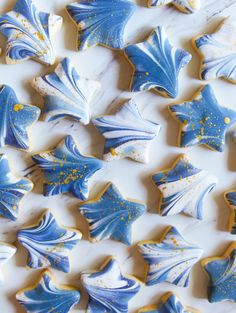 blue and white decorated cookies are arranged on a counter top with gold sprinkles