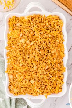 a casserole dish filled with shredded cheese on top of a marble countertop