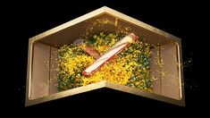 an open box filled with yellow flowers on top of a black background