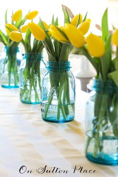 yellow tulips in mason jars lined up on a table with checkered cloth