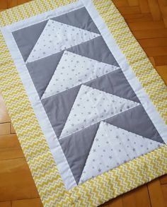 a quilted table runner with yellow and gray chevrons on the edge,