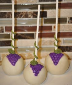 three white cake pops with purple grapes on them