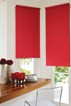 two red roller shades in a dining room with white walls and wooden counter top area