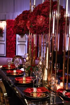 the table is set with red flowers and gold candlesticks for an elegant dinner