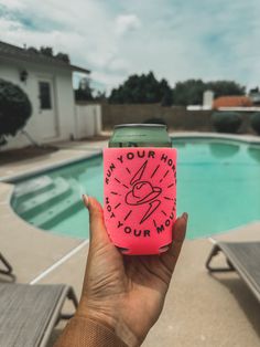 someone holding up a pink can cooler near a swimming pool