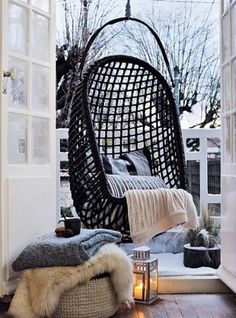 a black hanging chair sitting on top of a wooden floor next to a white door