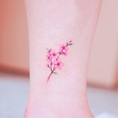 a small pink flower tattoo on the ankle