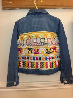 Mini Indie embroidered denim jackets are handmade by Esme in Manchester UK.  Age 4-5 years  Super soft stretch denim  Stone washed denim jacket with ruffle detail at front and center front button fastening. Embroidered back with gorgeous multicoloured Indian braid fabric.  EsmeAndTheEye upcycles second-hand denim jackets and gives them a new lease of life by adding beautiful Indian braid and embroidered textiles.  Each piece is hand picked by Esme and loving re-worked to create a hippie unique j Spring Festival Denim Blue Outerwear, Embroidered Long Sleeve Denim Jacket For Summer, Embroidered Long Sleeve Summer Denim Jacket, Multicolor Denim Jacket For Spring, Spring Multicolor Denim Jacket, Hippie Patchwork Cotton Denim Jacket, Hippie Cotton Patchwork Denim Jacket, Spring Festival Outerwear With Geometric Embroidery, Multicolor Patchwork Cotton Denim Jacket