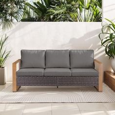 a couch sitting on top of a patio next to potted plants