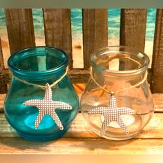 two glass jars with starfish charms are sitting on a wooden table next to each other