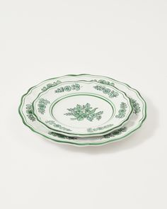 two green and white plates sitting side by side on top of each other, one is empty