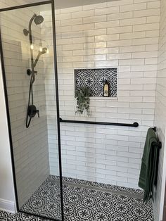 a walk in shower sitting next to a white tiled wall and black accents on the floor