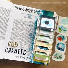 an open bible with paper and stickers on it, next to some crafting supplies