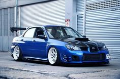 a blue car parked in front of a garage door