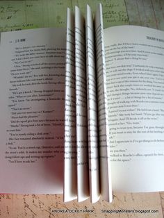 three folded books sitting on top of a table next to each other with writing on them