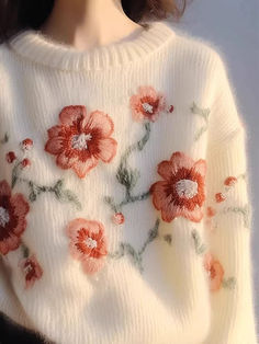 a close up of a doll wearing a sweater with flowers on the front and back