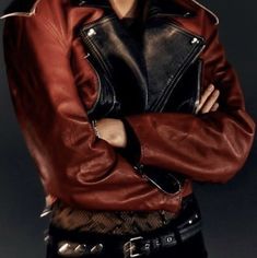 a woman wearing a red leather jacket posing for a photo with her arms crossed in front of her chest