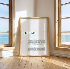 an ocean poster is on the floor in front of two windows and a window sill