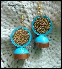 two blue and brown earrings on top of a white knitted surface with gold circles