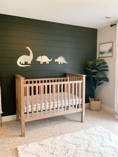 a baby's crib with dinosaur decals on the wall next to it