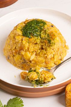 an omelet on a plate with a spoon next to some other food items