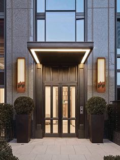 an entrance to a building with two large planters on either side and the doors open