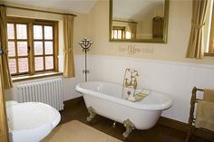 a bathroom with a claw foot bathtub and mirror on the wall, next to a window