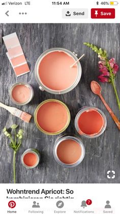 some pink paint is sitting on a table next to flowers and other things that are around it