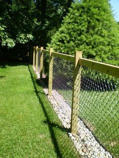 the fence is made of wood and has rocks in it, along with green grass