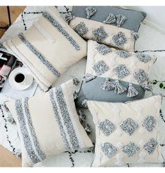 four pillows with tassels and lace on them sitting on a rug next to a cup of coffee