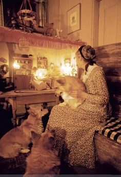 a woman sitting on a bench with two dogs in front of her and candles behind her