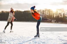 two girls are skating in the snow on their skates and one girl is wearing an orange jacket