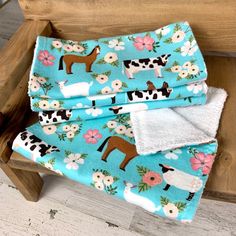 three farm animals and flowers on blue fabric with white trim, sitting on a wooden bench