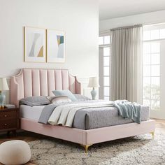 a bed with pink headboard and foot board in a white room next to a window