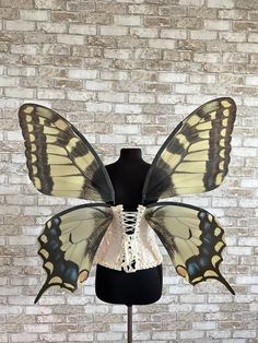 a mannequin with two large yellow and black butterflies on it's wings