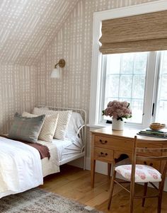 a bed room with a neatly made bed next to a window and a wooden desk