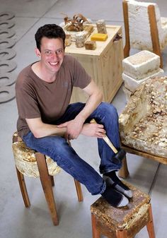 a man is sitting on a chair with tools in his hands and smiling at the camera