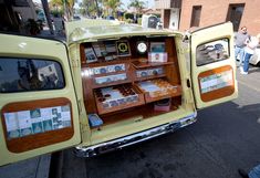 an old yellow truck with many items in it's back door, parked on the street