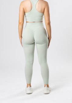 the back view of a woman in light green sports bra top and leggings