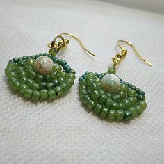 These beautiful earrings are a perfect addition to any jewelry collection. Crafted with attention to detail, they feature astunning green beads  and gold tone hook closure. The beaded design is perfect for any occasion and adds a touch of elegance to any outfit. The earrings are made by an Artisan and are of high quality. They are perfect for women who appreciate handcrafted jewelry. The earrings are made with glass beads and have a hook closure. They are 1.5 inches long and have a hook for easy wear. These earrings are perfect for any occasion and are a must-have for anyone who loves beaded jewelry. Beaded Shell, Green Beads, Handcrafted Artisan Jewelry, Earrings Green, Shell Earrings, Green Bead, Green Gold, Easy Wear, Artisan Jewelry