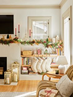 a living room decorated for christmas with stockings on the mantel, candles and other holiday decorations