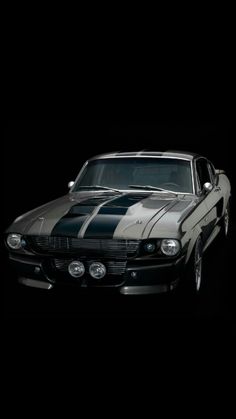 an old mustang muscle car with stripes painted on it's hood in the dark