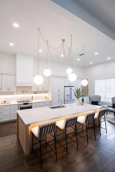 a large kitchen with white cabinets and counter tops next to a dining room table that has four chairs around it