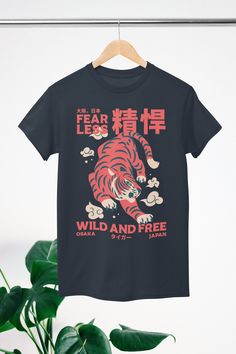 About The Design: This illustration showcases a tiger in a Japanese streetwear style, merging traditional elements with contemporary fashion. The tiger's fierce expression and dynamic pose encapsulate its untamed spirit, while the modern, stylized details embody an urban aesthetic. The bold text "FEARLESS" is written in both English and Japanese characters, highlighting the tiger's indomitable nature. The blend of cultural motifs and streetwear flair creates a striking visual, symbolizing confid Fierce Expression, Japanese Tiger, Harajuku Shirt, Asian Streetwear, Dynamic Pose, Japanese Shirt, Tiger Shirt, Urban Aesthetic, Aesthetic Shirt