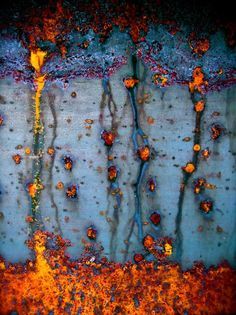 rusted metal surface with orange and blue paint on it's edges, as seen from above