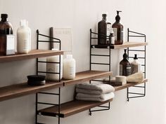 bathroom shelves with soaps, lotion and other items on them against a white wall