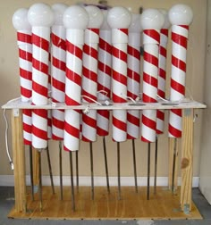 several red and white candy canes are stacked on top of each other in front of a wall